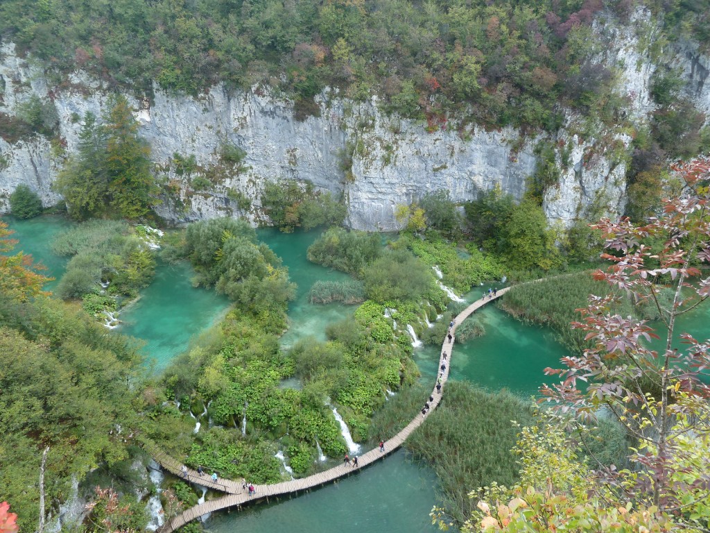 View of woodland, cliffs, turquoise lakes and wooden walkway with tourists in Plitvicka Jezera National Park, Croatia